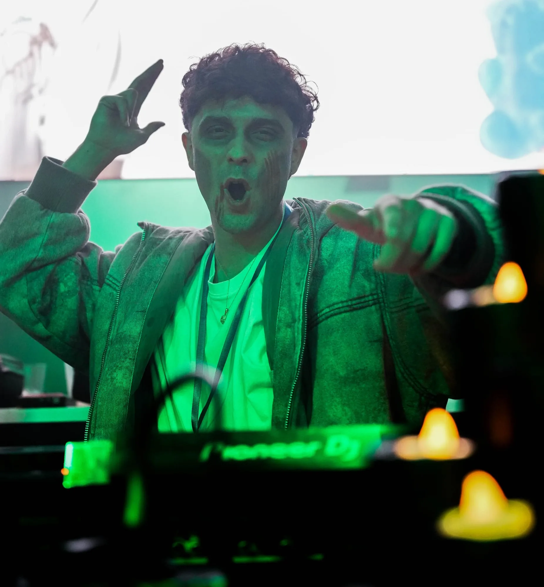 DJ al micrófono en la cabina de Halloween Fest, con la pista iluminada al fondo